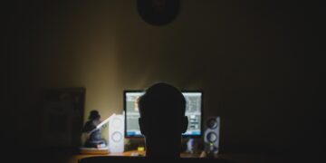 Mann vor PC in einem dunklen Raum