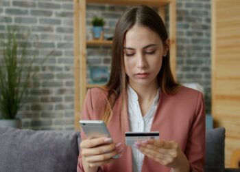 Frau in Arbeitsklamotten mit Kreditkarte